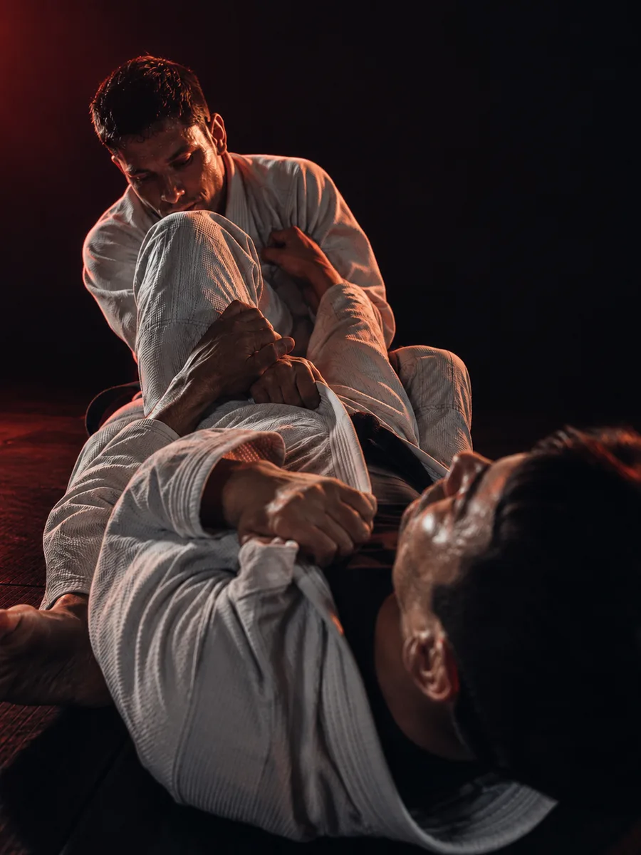 Praticantes de Jiu-Jitsu em disputa no chão, academia de Jiu-Jitsu